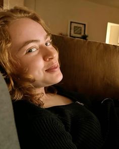 a woman sitting on a couch with her eyes closed and looking up at the camera