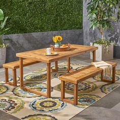 a wooden table with two benches on top of it next to a potted plant