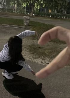 a person kneeling down on the ground with their hand extended out to touch something in front of them