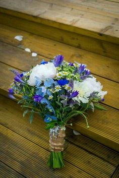 a bouquet of blue and white flowers sitting on top of a wooden bench next to steps