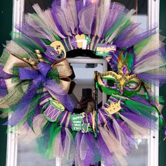 a purple and green mardi gras wreath with a mask on the front door