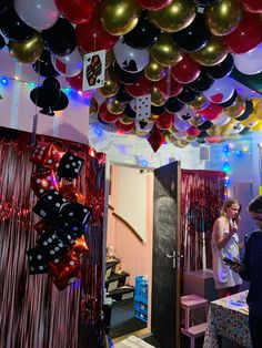 a room with balloons and streamers hanging from the ceiling, while two women look on