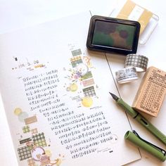 an open notebook with japanese writing on it next to a fountain pen and ink roller