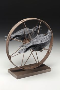 two birds are sitting in the center of a spinning wheel on top of a wooden base