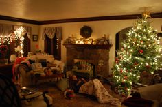 a living room filled with furniture and a christmas tree in front of a fire place