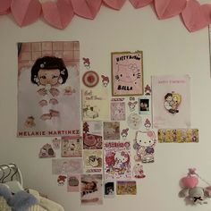 there are many pictures on the wall with pink hearts hanging above it and a teddy bear next to them