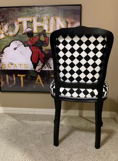 a black and white checkered chair sitting in front of a painting on the wall