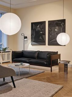 a living room filled with furniture and two large white lamps hanging from the ceiling above