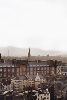 an aerial view of a city with buildings and mountains in the backgrouds