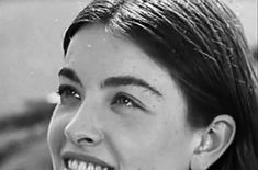 black and white photograph of a woman with long hair smiling at someone in the background