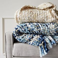 three blankets stacked on top of each other on a couch in front of a white wall