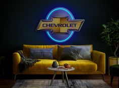 a yellow couch sitting in front of a blue chevrolet logo on the wall above it