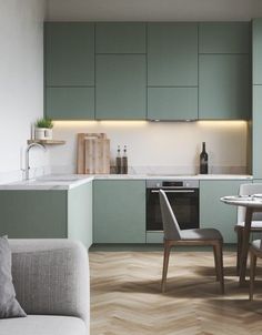 a kitchen and dining area with green cabinets, white counter tops and wood flooring