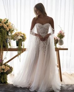 a woman in a wedding dress standing next to flowers