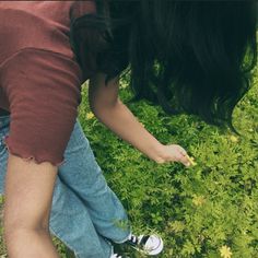 two people reaching for something in the grass