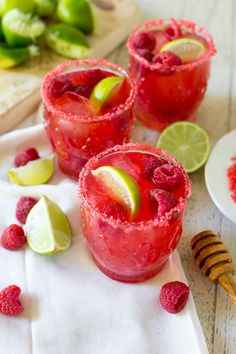 two glasses filled with raspberry margaritas and lime slices