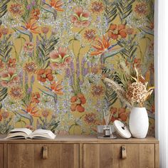 an orange floral wallpaper with white vases and books on a wooden cabinet in front of it