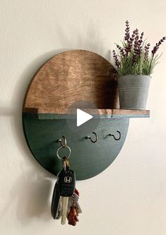 a wooden shelf with two key hooks and a potted plant on top of it