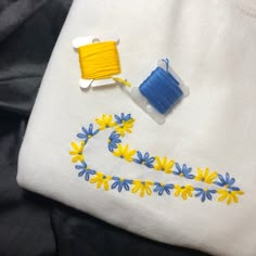 a white shirt with blue and yellow flowers on it next to a spool of thread