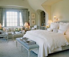 a large bed sitting in the middle of a bedroom next to two lamps on either side of it