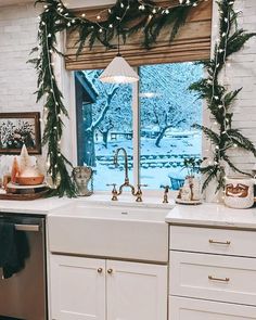 a kitchen decorated for christmas with wreaths and garland on the window sill over the sink