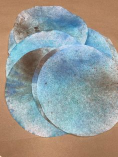 three blue plates sitting on top of a brown paper covered tablecloth with circles painted on them