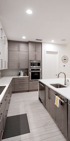 a modern kitchen with stainless steel appliances and white counter tops, along with gray cabinets