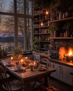 a dining room table is set with plates and candles in front of a fireplace that looks out onto the water