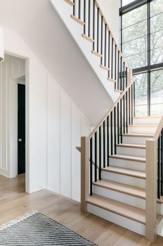 the stairs are made of wood and have black railings on each side, along with white painted walls