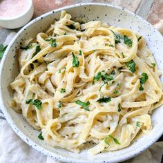 a white bowl filled with pasta and parsley