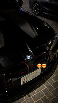 two cars parked next to each other in a parking lot with smiley faces on the hood