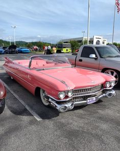 an old pink car parked in a parking lot