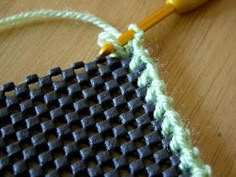 a close up of a piece of fabric with a knitting needle in the middle, on top of a wooden table