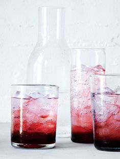 three glasses filled with red liquid next to a bottle