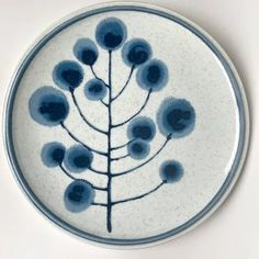 a blue and white plate with a plant on the front is shown in this image