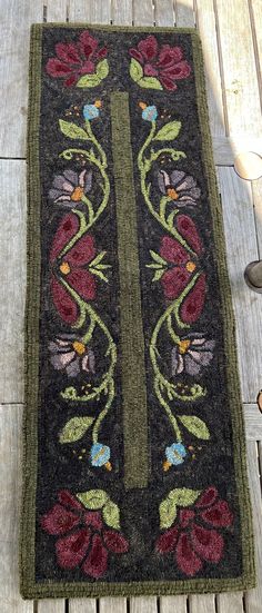 an old rug with flowers on it sitting on a wooden floor next to a pair of shoes