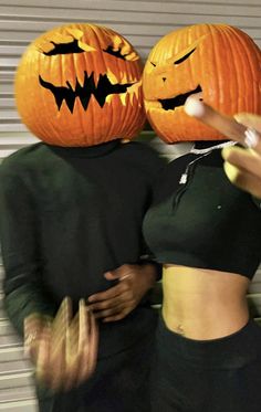 two people standing next to each other wearing pumpkin heads