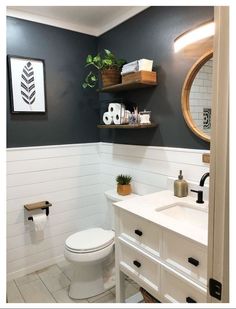 a white toilet sitting under a bathroom mirror next to a sink and shelf above it