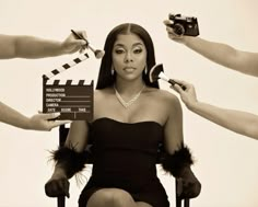 a woman sitting in a chair while holding a camera and some other hands around her