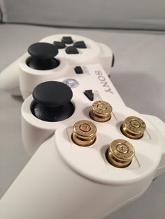 two video game controllers sitting next to each other on top of a table with buttons