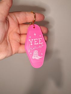 a hand holding a pink keychain that says yee yah