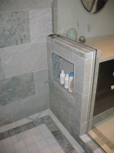 a bathroom with gray tiles and white fixtures on the shower wall, along with soap dispensers