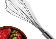 a whisk and strawberries in a wooden bowl on a white surface next to a metal beater