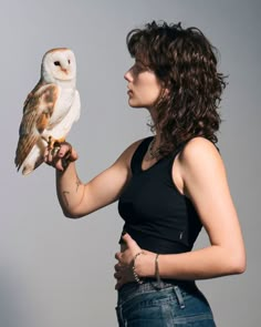 a woman holding an owl in her right hand