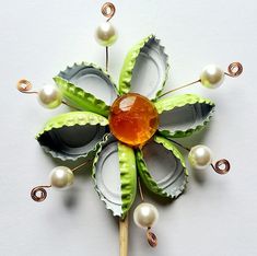 a brooch with pearls and green leaves on it's side, sitting on a white surface