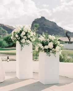 two tall white vases with flowers in them