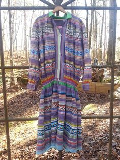 a colorful dress hanging on a fence in the woods