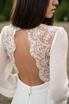 the back of a woman's wedding dress with lace detailing and buttons on it