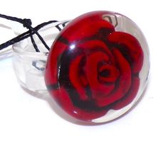 a red rose in a glass ball on a black cord with a white bead