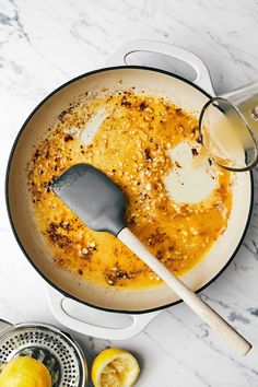 a pan filled with food next to lemons and a spatula